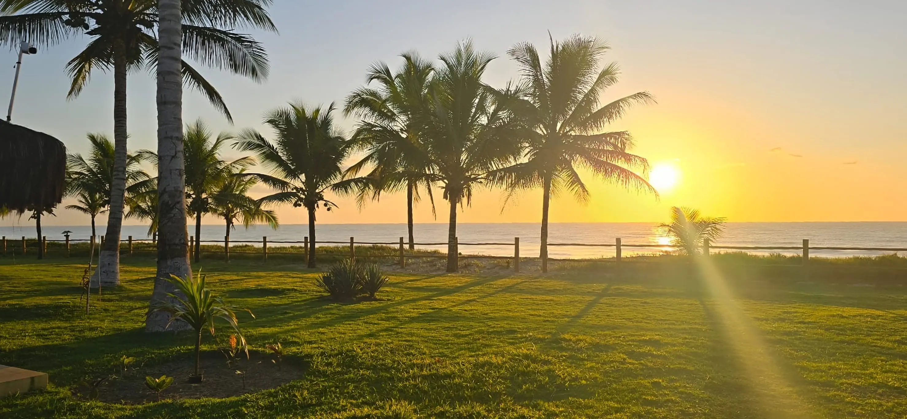 Pôr do sol no gramado do Bangalô Miramar, com o mar ao fundo