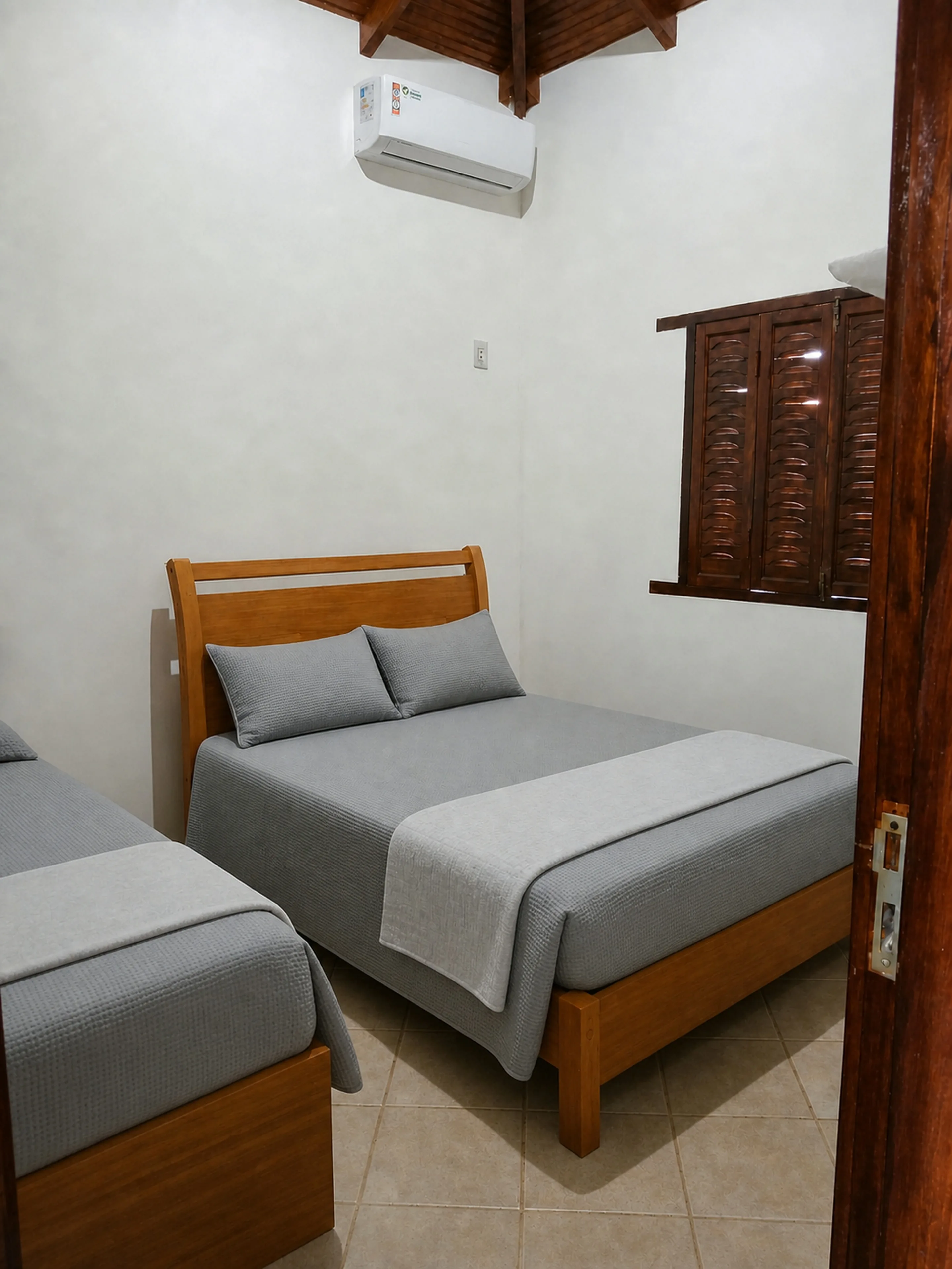 Quarto preparado com cama de casal e cama de solteiro no Bangalô Paraíso dos Coqueiros