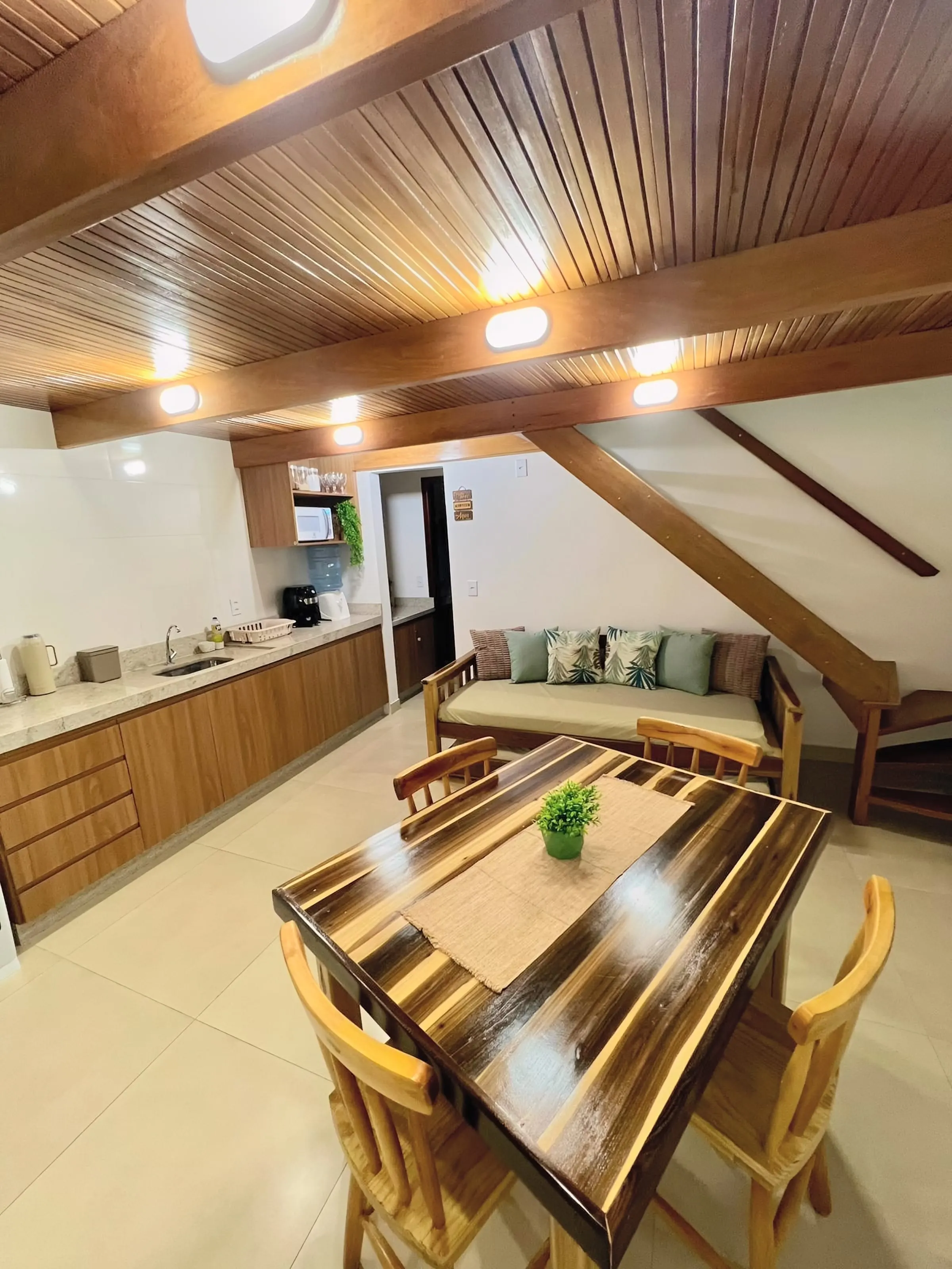 Sala do Bangalô Miramar com sofá, mesa de jantar e forro de madeira