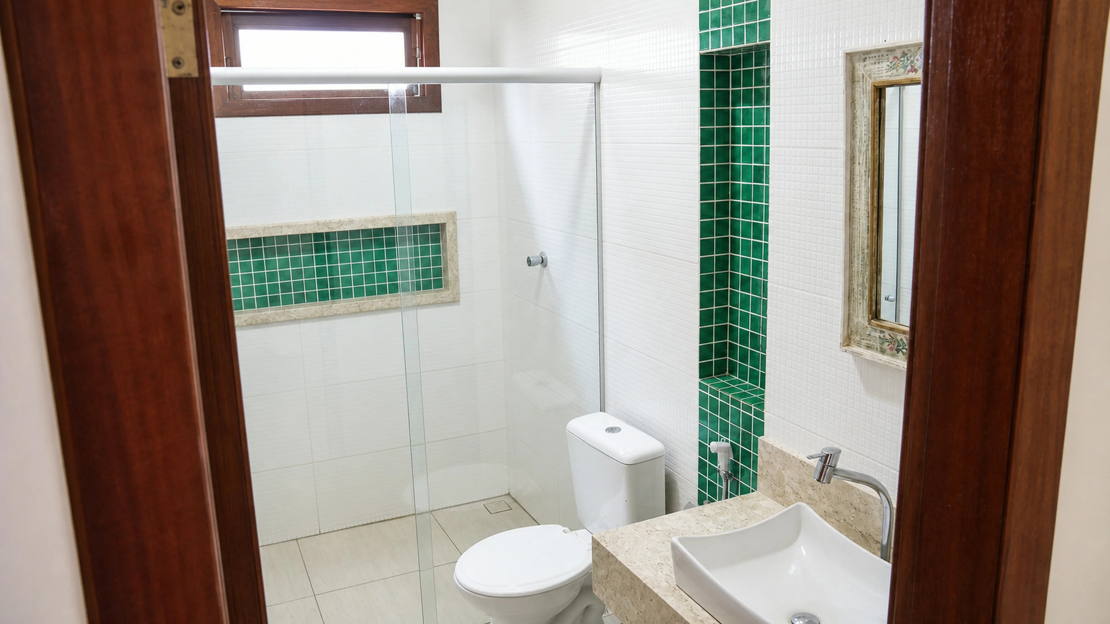 Banheiro completo com box de vidro e acabamento verde na Casa Paulo Filho e Neto
