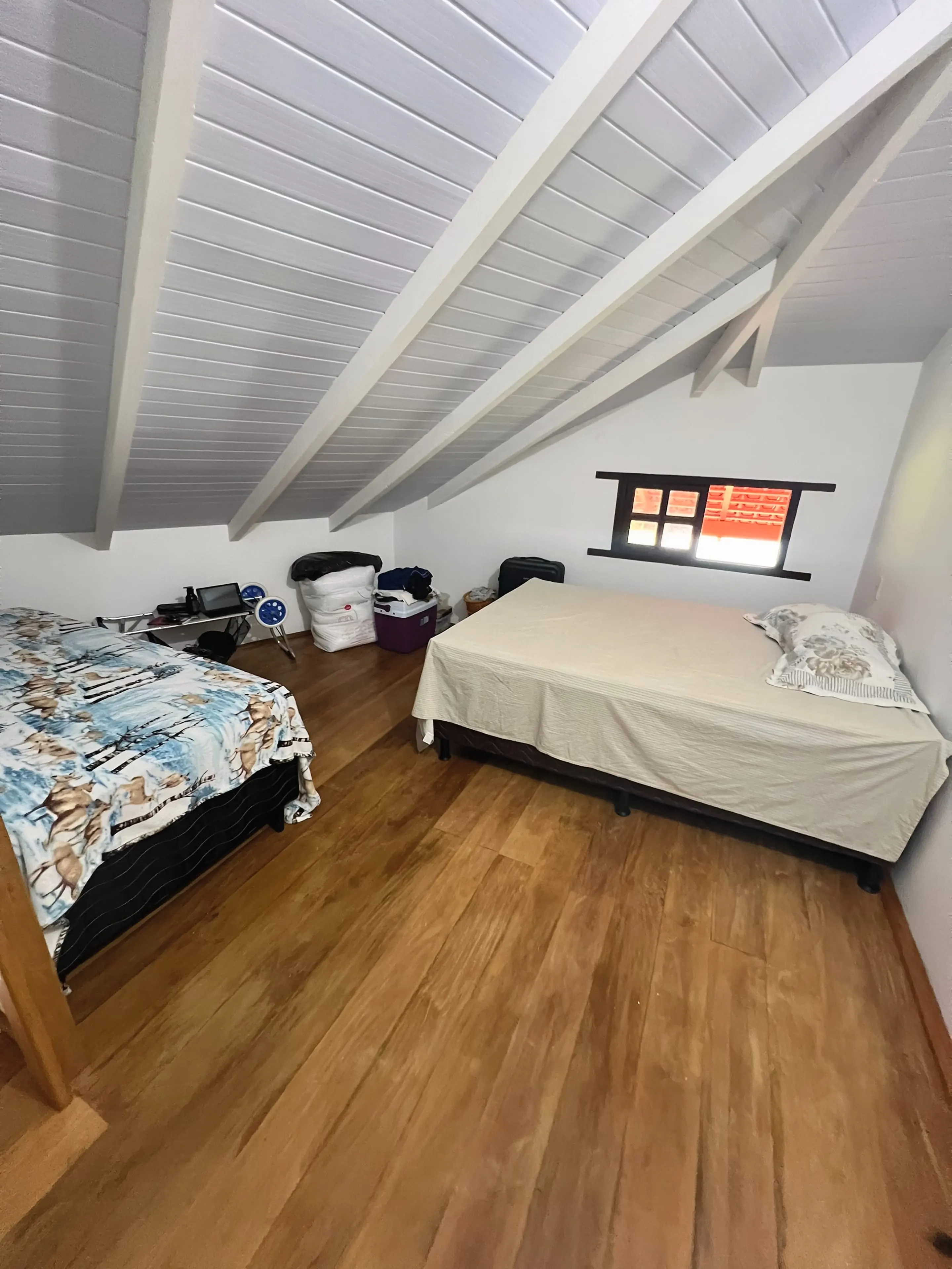 Mezanino do Bangalô Miramar com teto inclinado e piso de madeira