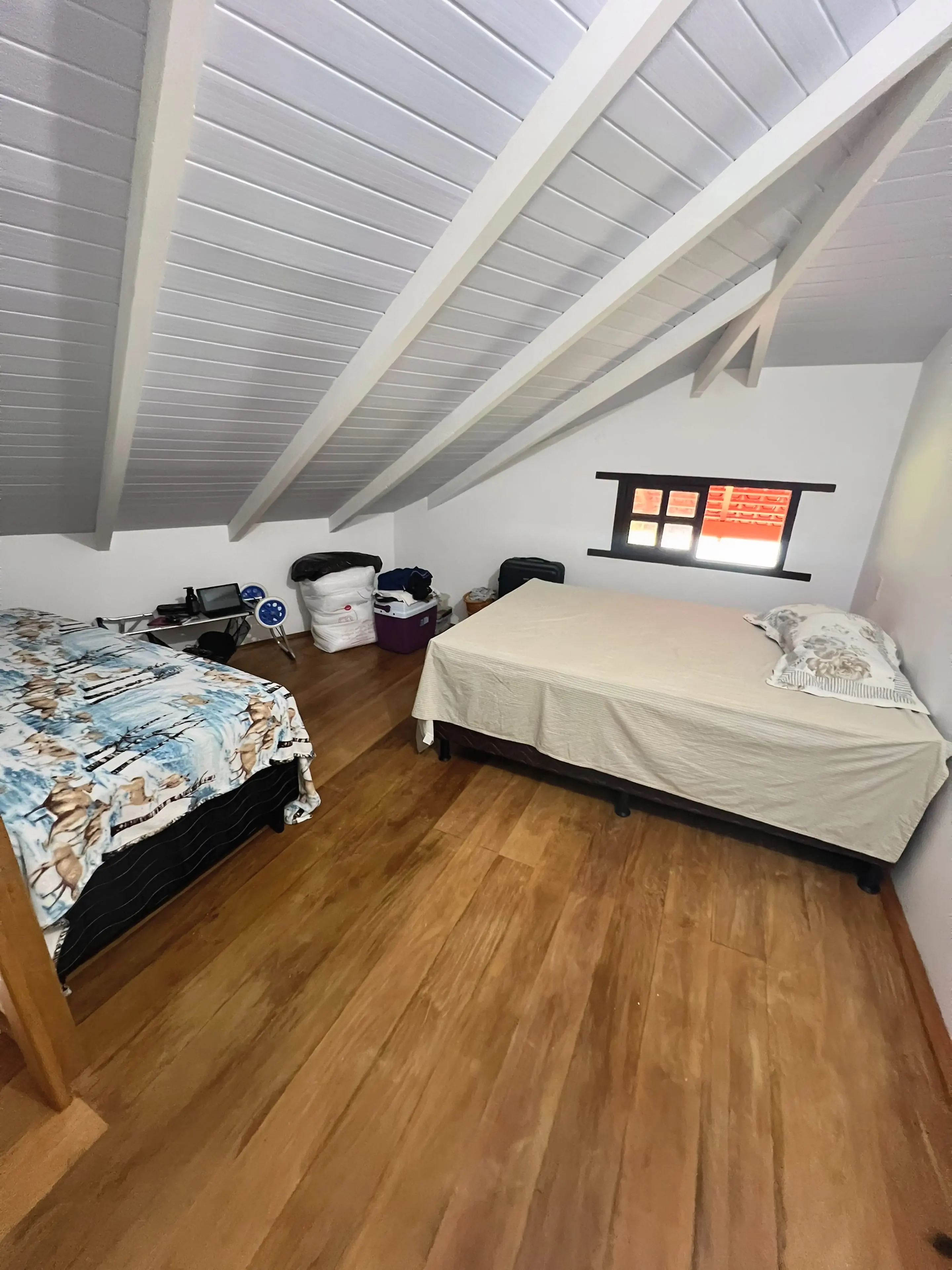 Mezanino do Bangalô Miramar com teto inclinado e piso de madeira