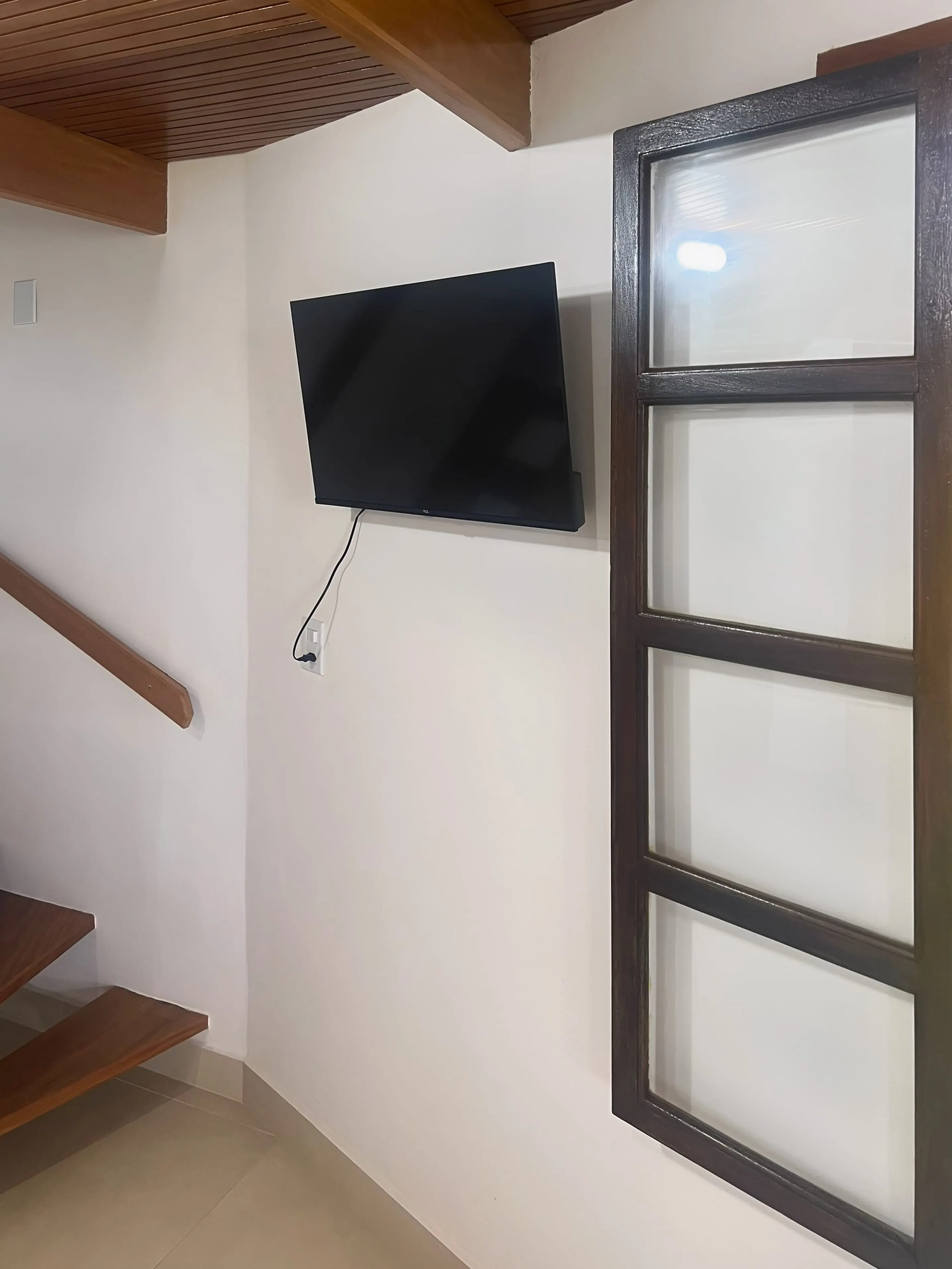Escada para o mezanino e TV na parede do Bangalô Miramar