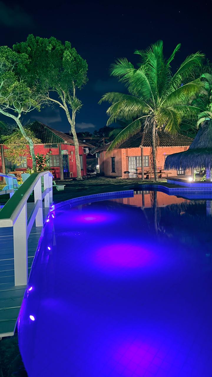Bangalô Paraíso dos Coqueiros — piscina iluminada à noite